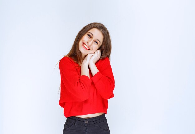 Fille en chemise rouge unissant les mains avec un visage joyeux.