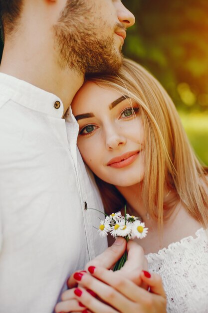 fille avec des cheveux clairs et une robe blanche dans une forêt ensoleillée avec son petit ami