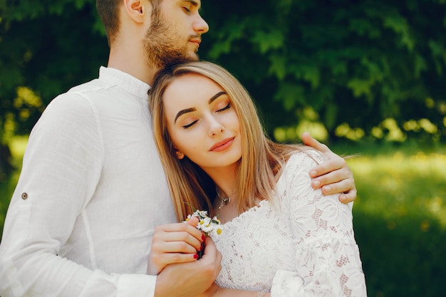 fille avec des cheveux clairs et une robe blanche dans une forêt ensoleillée avec son petit ami