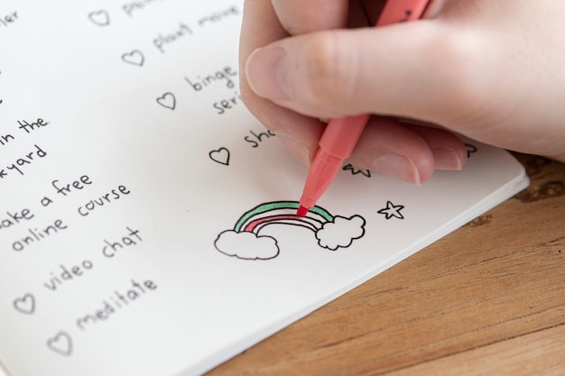 Fille colorier un doodle arc-en-ciel dans un cahier