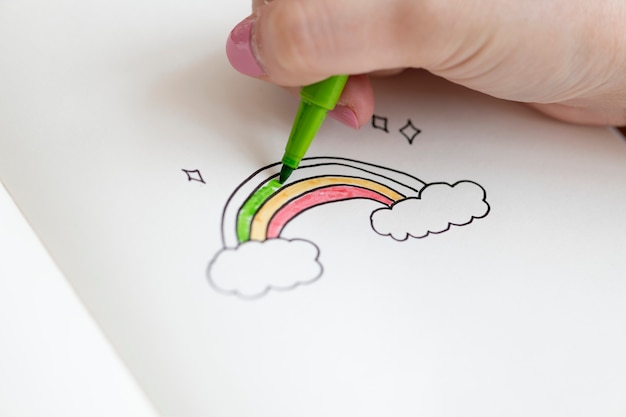 Photo gratuite fille colorier un doodle arc-en-ciel dans un cahier