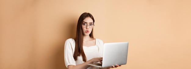 Une fille concernée dans des verres regarde l'appareil photo confus travaillant sur un ordinateur portable ayant des problèmes avec le personnel informatique