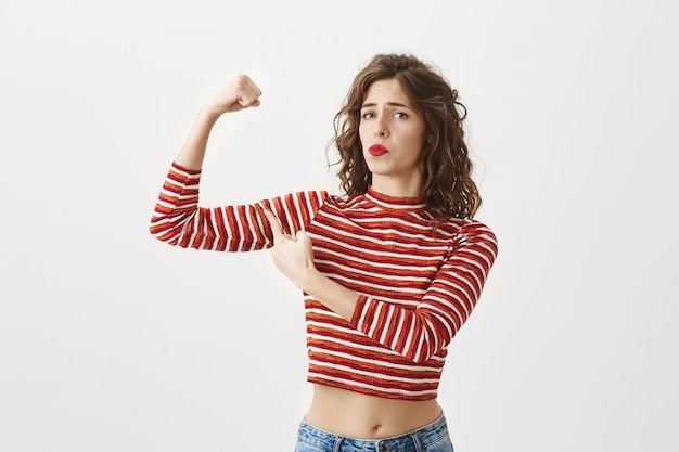 Photo gratuite fille confiante fléchit les biceps, montre ses muscles après la gym