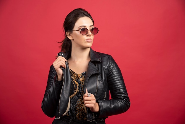 Fille Cool En Veste En Cuir Noir Et Lunettes De Soleil A L'air Stricte Et Exigeante.