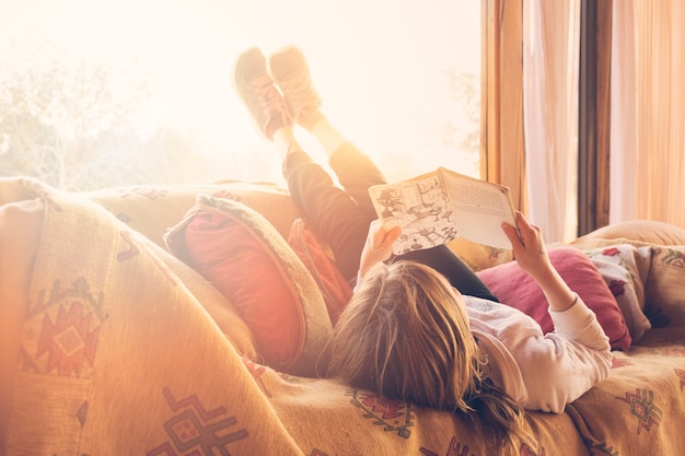 Photo gratuite fille couchée sur un livre de lecture de canapé