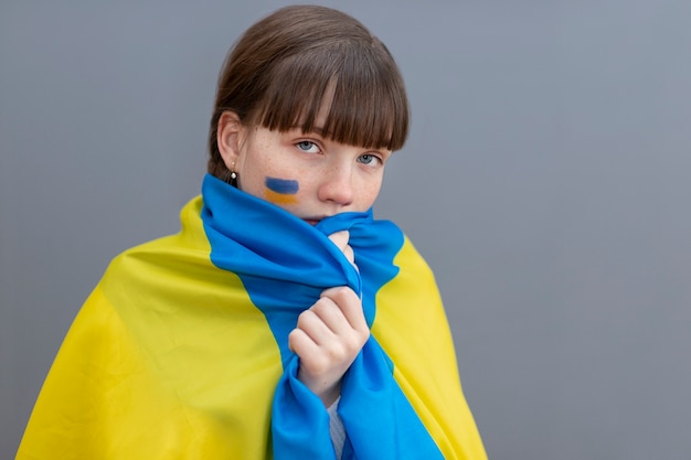 Photo gratuite fille de coup moyen couvrant avec le drapeau ukrainien