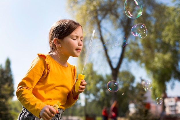 Fille de coup moyen faisant des bulles de savon