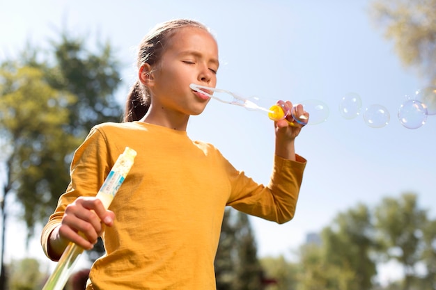 Fille de coup moyen faisant des bulles de savon