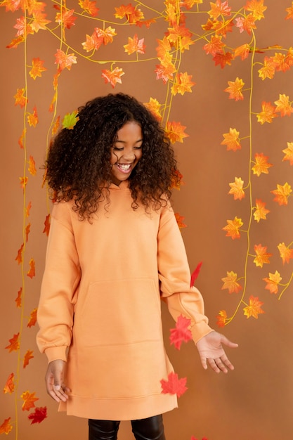 Fille de coup moyen posant avec des feuilles