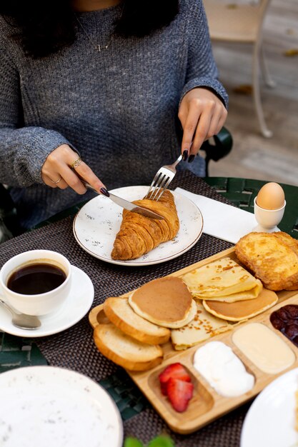 Fille coupe un croissant au petit déjeuner