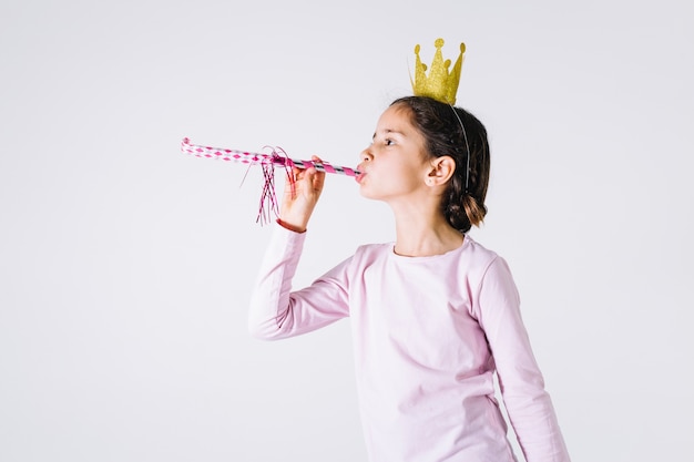 Fille en couronne soufflant corne de fête