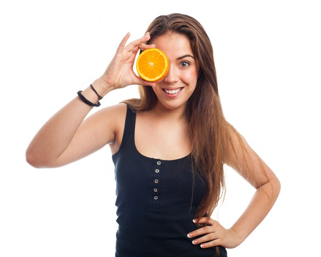 Fille couvrant ses yeux avec une orange,