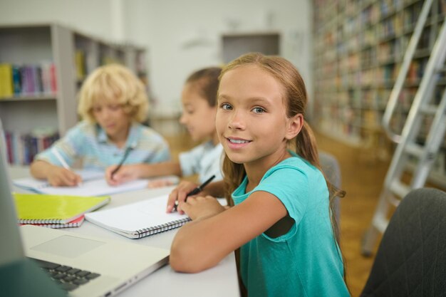 Fille avec un crayon et un cahier en regardant la caméra