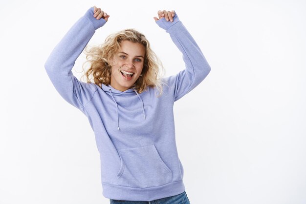 Fille dans l'ambiance de Noël s'amusant et faisant la fête dansant sans soucis avec les mains levées s'amusant à crier de joie et de joie à s'amuser alors que le week-end est enfin arrivé portant un joli sweat à capuche chaud