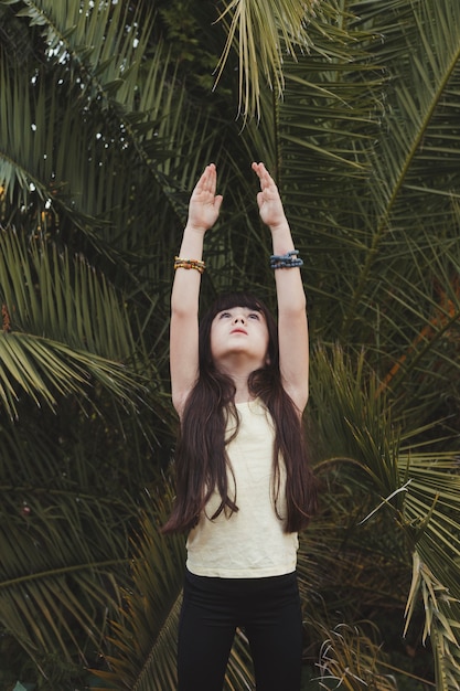 Photo gratuite fille dans l'arbre pose près de la paume