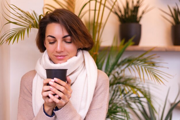 Une fille dans un café confortable se réchauffe avec une tasse de café chaud