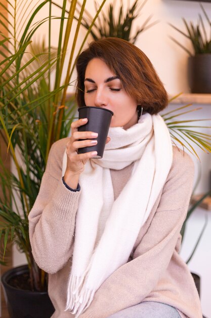 Une fille dans un café confortable se réchauffe avec une tasse de café chaud