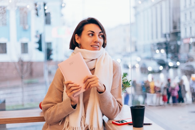 Une fille dans un café confortable se réchauffe avec une tasse de café chaud