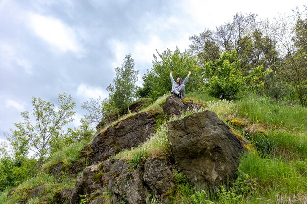 Une fille dans la forêt printanière est assise sur une pierre parmi la verdure.