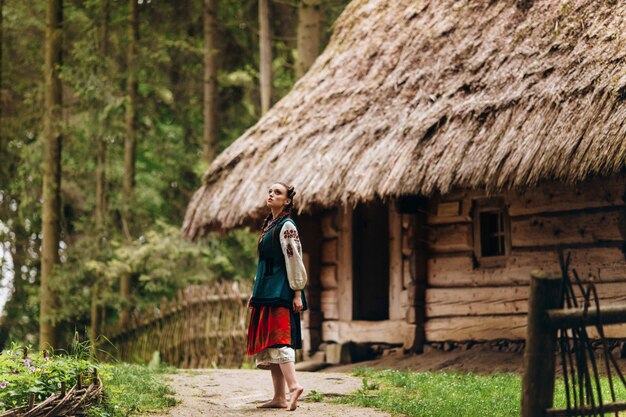 Fille dans une robe brodée est debout dans la cour et regarde dans le ciel