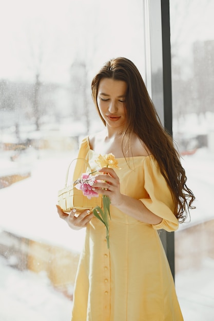 Fille dans une robe jaune avec un panier dans ses mains célèbre Pâques