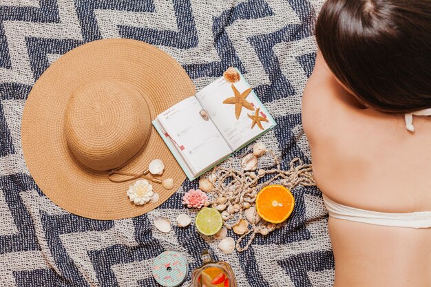 Fille dans une serviette de plage avec agenda et chapeau