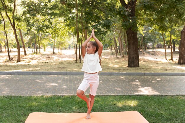 Fille debout sur une jambe dans la nature plein coup