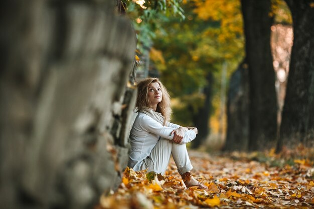 fille décontractée assis sur des feuilles sèches