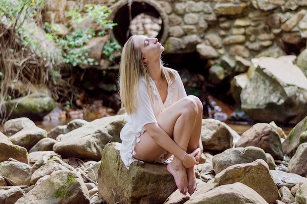 Photo gratuite fille décontractée assis sur un rocher à l'extérieur