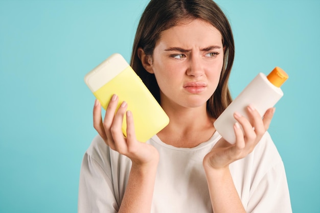 Fille déçue avec des déchets plastiques dans les mains regardant tristement loin sur fond coloré isolé