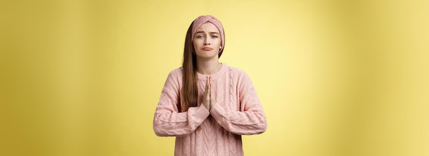 Photo gratuite une fille délibérément triste en pull pressant les paumes ensemble dans la prière en train de poupée en train de prier pour de l'aide en demandant