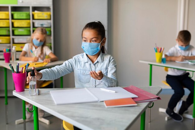 Fille désinfectant dans la salle de classe