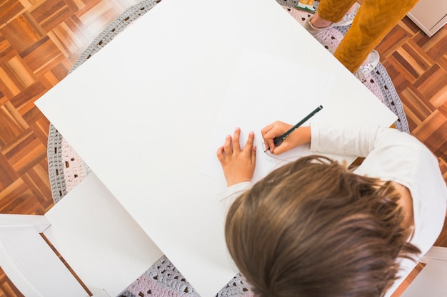 Fille dessin sur une petite table