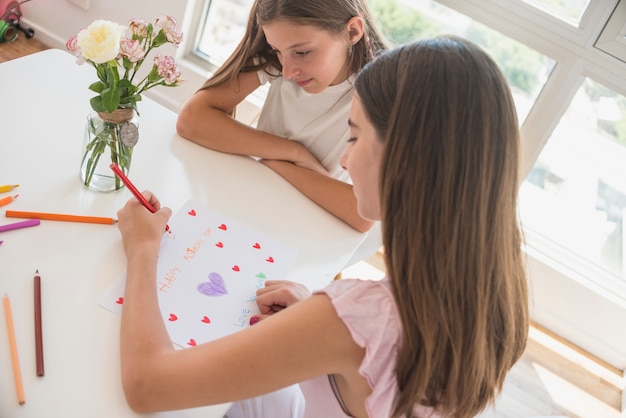 Fille dessinant des coeurs rouges sur papier