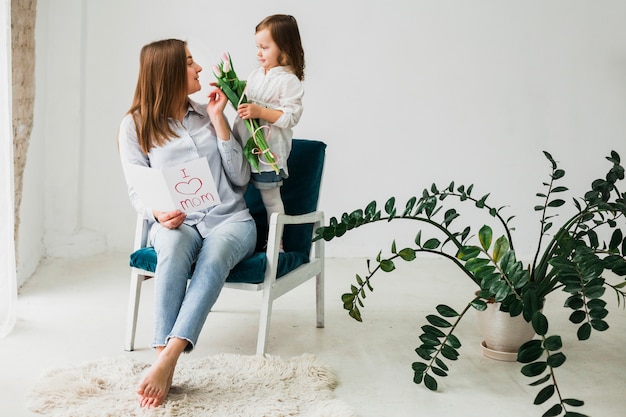 Fille donnant des fleurs à la mère avec carte de voeux