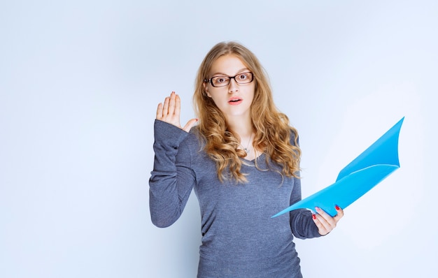 Fille Avec Un Dossier Bleu Levant La Main Pour Attirer L'attention.