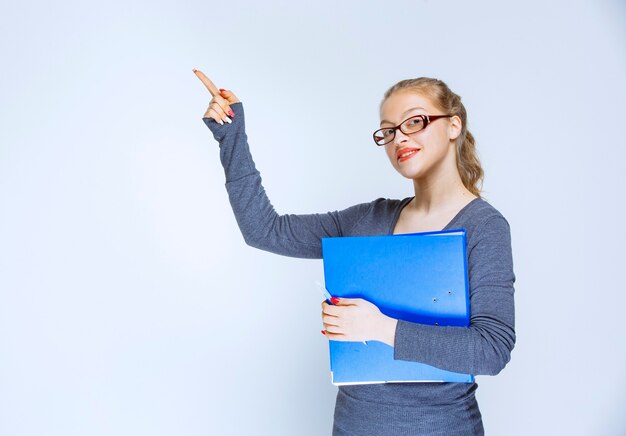 Fille avec un dossier bleu pointant au-dessus.