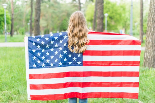 Fille avec un drapeau américain dans la nature par derrière