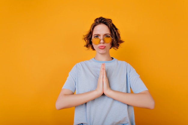 Fille Drôle Avec Des Cheveux Ondulés Brun Foncé Debout Sur Un Espace Jaune Avec Une Expression De Visage Triste