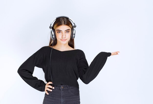 Fille avec des écouteurs pointant vers quelque chose sur le côté droit. photo de haute qualité