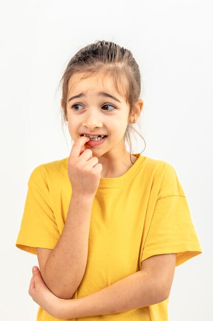 Photo gratuite une fille effrayée et anxieuse se mord les ongles sur un fond blanc isolé.