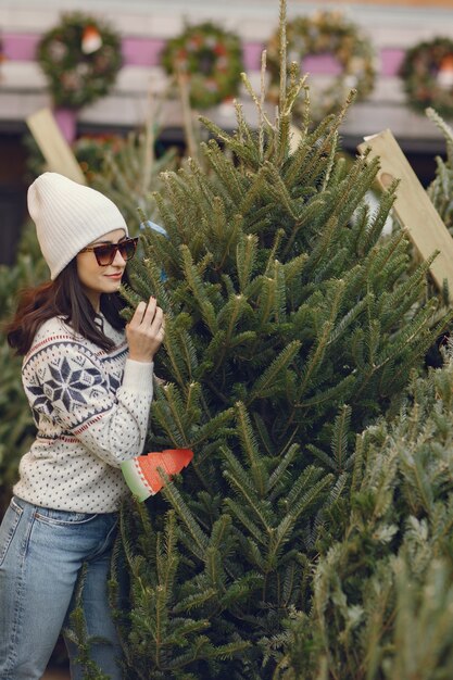 Fille élégante achète un arbre de Noël.