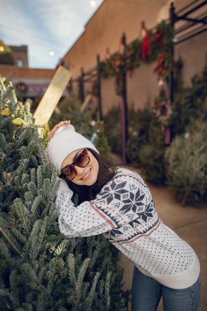 Fille élégante achète un arbre de Noël.