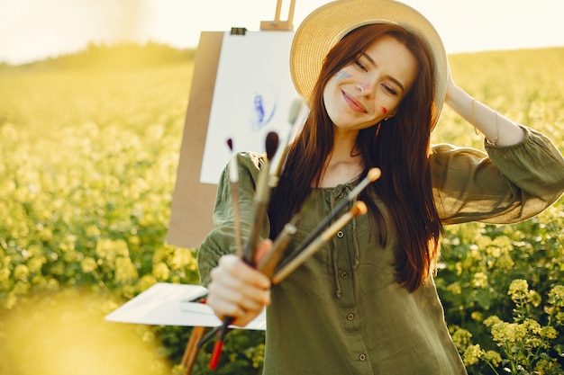 Fille élégante et belle peinture dans un champ