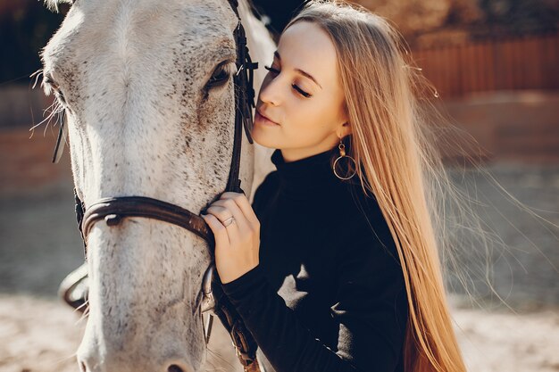 Fille élégante avec un cheval dans un ranch