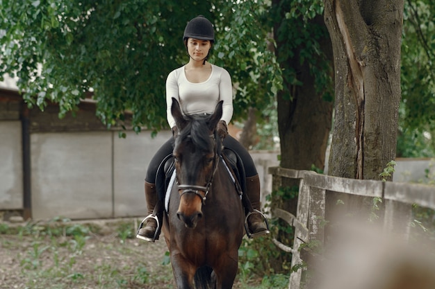 Fille élégante dans une ferme avec un cheval