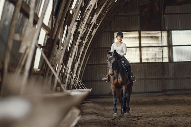 Fille élégante dans une ferme avec un cheval