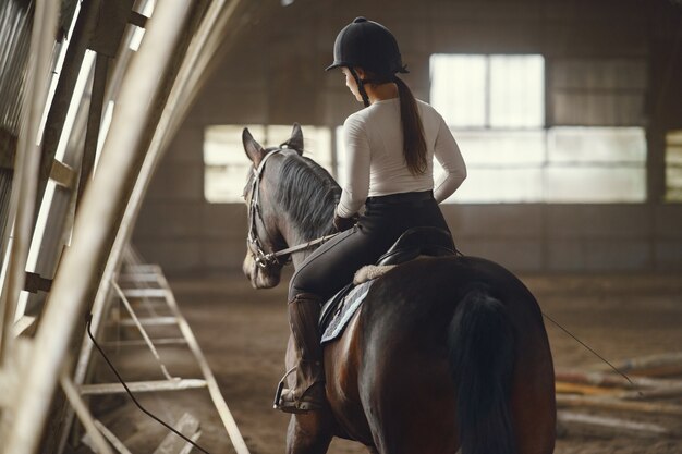 Fille élégante dans une ferme avec un cheval