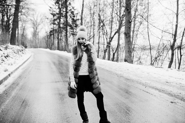 Fille élégante en manteau de fourrure et couvre-chef à la journée d'hiver sur la route