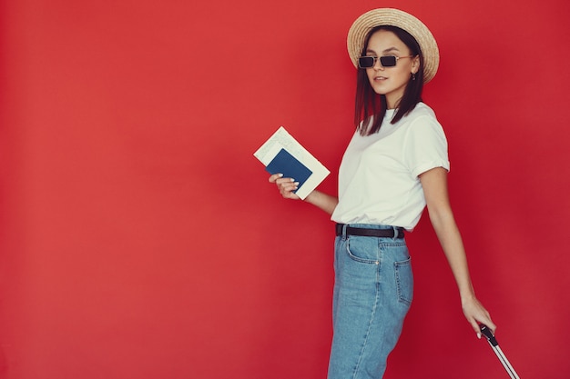 Photo gratuite fille élégante posant avec des équipements de voyage sur un mur rouge